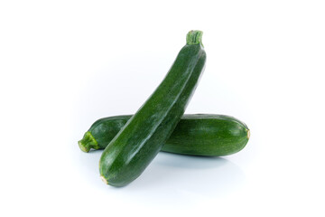 Zwei grüne Zucchini, schräge übereinander gekreuzt liegend auf einem weißen Hintergrund