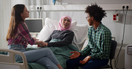 Young people visiting ill female friend in hospital ward