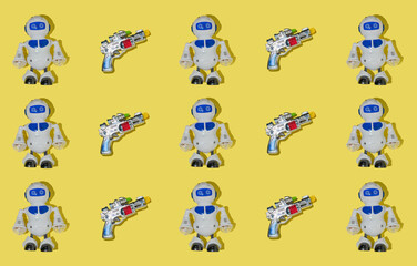 Creative pattern made with space gun and robot toy on bright yellow background. Fun creative idea. Retro layout with childrens toys.