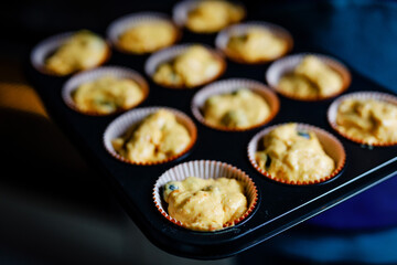 Overhead view of a baking tray with freshly prepared plain carrot and blueberry muffins.