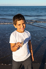 Funny kid showing a crab leg on the beach