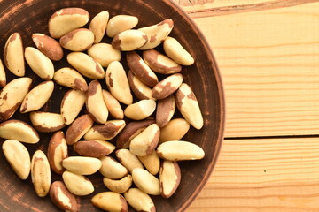Several delicious organic Brazil nuts in a ceramic plate , top view.