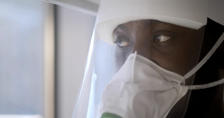 Fototapeta na wymiar Close up portrait of african doctor wearing respiratory mask and face shield in hospital