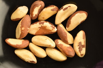 Obraz premium Several delicious organic Brazil nuts in a ceramic plate , top view.