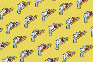 Creative pattern made with space gun toy on bright yellow background. Fun creative idea. Flat lay.