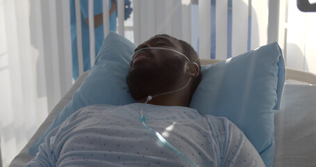 African-american male patient with nasal cannula having fever lying in hospital bed