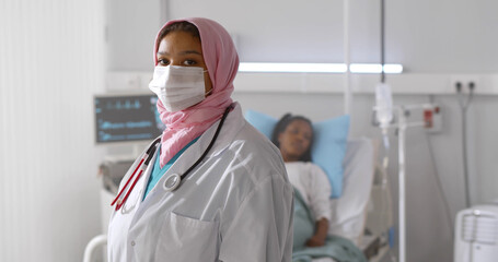 Portrait of arabian woman doctor in protective mask looking at camera working at hospital