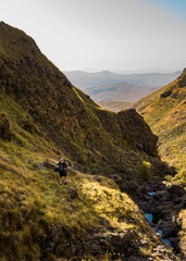 Hikers walking along a stream in the Drakensburg, South Africa. October 2019