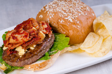gourmet kimchi angus beef burger with potato chips on the side