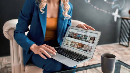 Cropped shot of professional female travel agent using laptop while offering tours to her clients in office