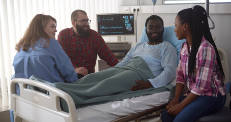 Diverse friends visiting sick african man in hospital ward