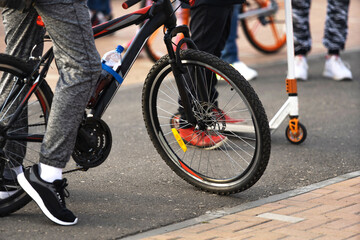 Naklejka premium Young people ride bicycles and scooters along the city streets. A hangout of teenagers leading an active lifestyle. Cropped frame. Beyond recognition