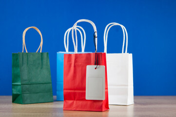 Colorful paper shopping bags on the floor against a blue wall background. Sale, consumerism, advertisement and retail concept