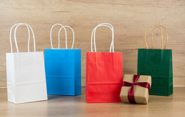 Colorful paper shopping bags on the floor against a wooden wall background