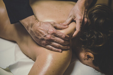Soft focus view of man massaging a woman in a wellness center. Oiled hands on a body relaxing the...