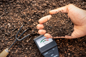 A fertile loam in the hands of a farmer man and a soil measurement in place.