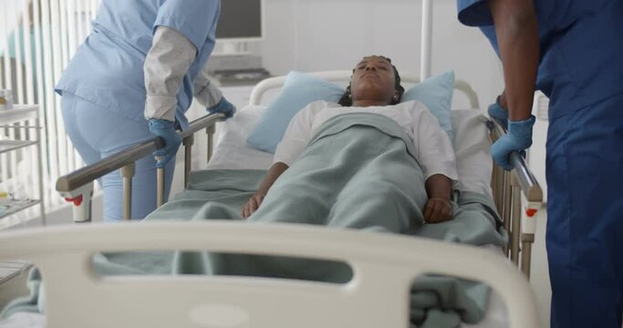 Medical team push emergency stretcher transporting afro woman patient in hospital.