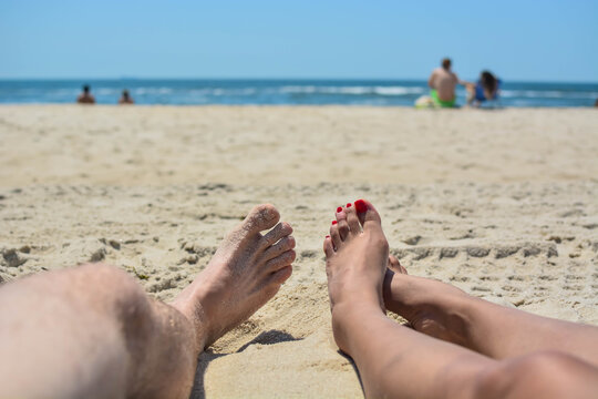 Summer fun couple showing there feen next to each other, while sun bathing on the beach