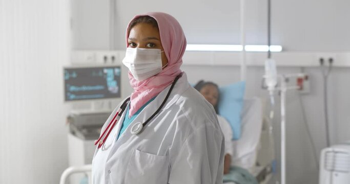 Portrait of arabian woman doctor in protective mask looking at camera working at hospital