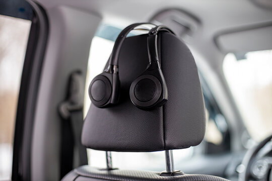 on-ear headphones hang on the headrest in the car. technology personal multimedia system in a modern premium car
