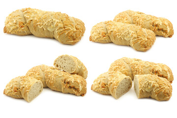 freshly baked spelt bread covered with grated cheese and a cut one on a white background