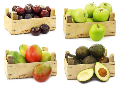 Red plums, freshly harvested "Granny Smith" apples, mango's and avocado's in a wooden crate on a white background 