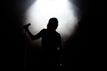 black silhouette of female singer with white spotlights in the background