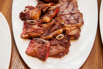 Sliced meat steak and ribs on a plate close-up. Macro. Defocus