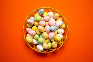Fototapeta na wymiar Colorful Easter eggs in the basket on orange background. Spring holidays concept