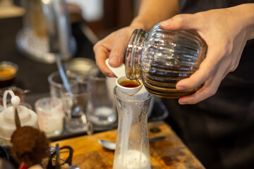 The bartender is using a white measuring spoon. Pour the honey into a glass with milk in the drink mix and design to add flavor to the drink.