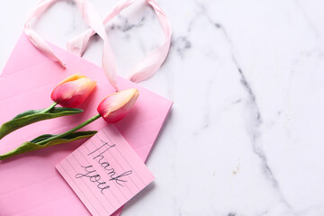 thank you message on sticky note with tulip flower on pink background 