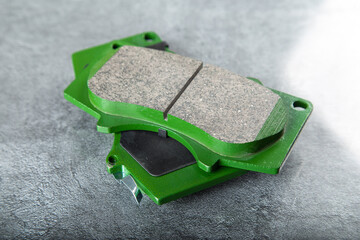 a set of new green brake pads on a gray table