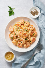 Pasta spaghetti with grilled shrimps bechamel sauce. Spaghetti with seafood rich cream. Cooking mediterranean food with savory prawns, top view, blue table, italian cuisine, vertical