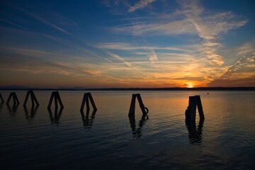 Sonnenuntergang am See mit Holzpfosten im Vordergrund