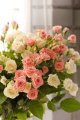 Bouquet of small pink and cream roses in a vase on the window