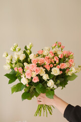 Bouquet of small pink and cream roses in female hands
