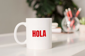 Hola sign in spanish language on the mug on business table