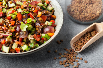 salad with lentils and vegetables in a deep plate on a dark gray background, vegetarian food