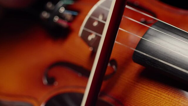 Musician plays a close-up of the violin strings. Bow string musical instrument. Concept of playing the violin.