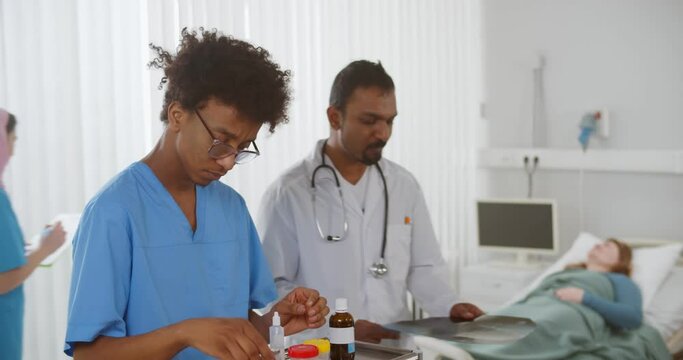 Indian doctor and african intern studying x-ray of patient in hospital ward