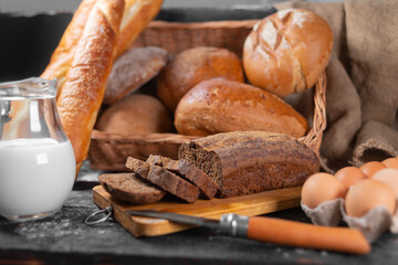 assortment of bakery, bran bread is on the kitchen board next to other types.