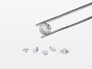 brilliant cut diamond held by tweezers isolated on white background