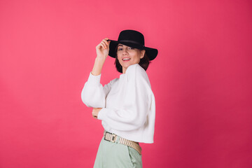 Stylish woman in casual white sweater and hat on pink red background isolated space smile cheerful moving positive