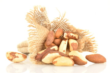Several delicious organic Brazil nuts on a jute bag, close-up, isolated on white.
