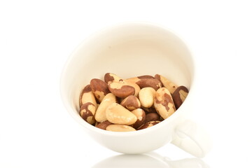 Several ripe organic Brazil nuts in a ceramic cup, close-up. The background is white.