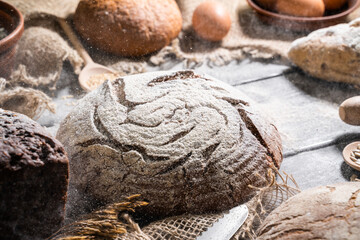 Bakery - gold rustic bread and buns on black background. Still life captured from above (top view, flat lay).