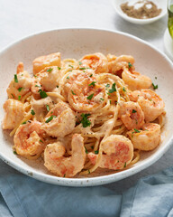 Pasta spaghetti with grilled shrimps bechamel sauce. Spaghetti with seafood rich cream. Cooking mediterranean food with savory prawns, macro side view, vertical, italian cuisine