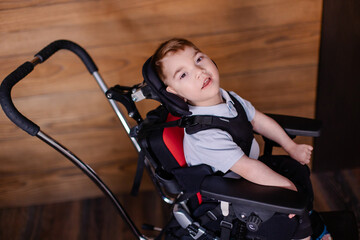 beautiful boy child in a special wheelchair. Toddler with cerebral palsy. Rehabilitation process at...