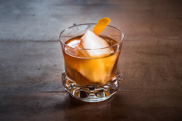 Old Fashioned Cocktail with Whiskey on a Wood Table with Orange Twist in an Elegant, Retro Crystal Glass Tumbler