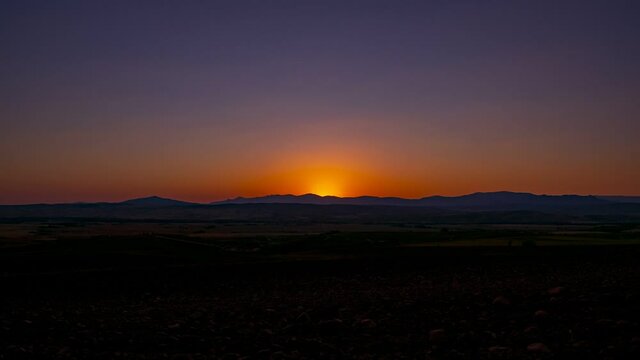 A beautiful time-lapse of a sun setting behind mountains in HD